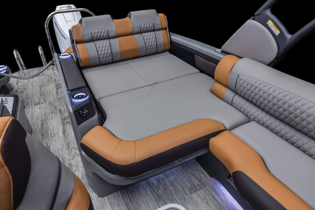 Image of a luxurious boat interior featuring a spacious Excalibur LTD Versatile Rear Bench Windshield with adjustable backrests. The seatbacks are equipped with electronic controls and built-in cup holders, all on a sleek, wood-patterned floor with ambient lighting.